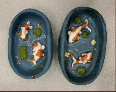 Two hand-painted clay dishes decorated with koi fish